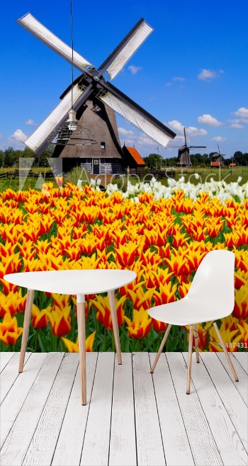 Bild på Traditional Dutch windmill with vibrant orange and yellow tulips